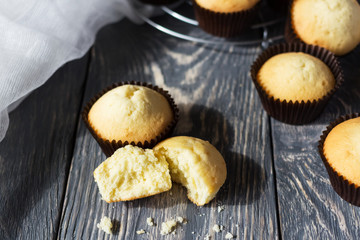 Baked cupcakes in molds, near broken cupcake, on gray surface
