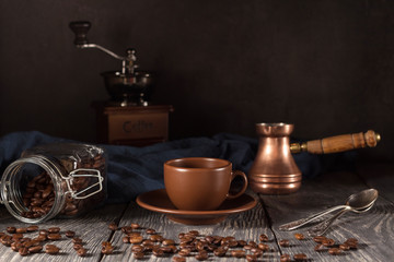 Cup and saucer, scattered coffee beans, coffee maker, isolated on black