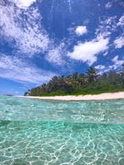 HALF UNDERWATER: Hot tropical sunrays shine on picturesque empty sandy beach.