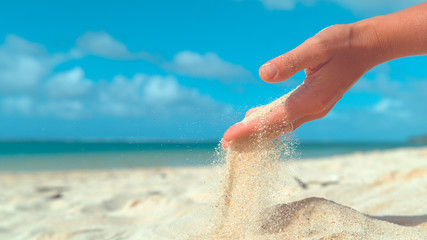 CLOSE UP: Tiny grains of sand get swept away from female hand by summer breeze