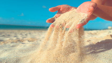 Fototapeta na wymiar CLOSE UP: Unrecognizable woman lets breeze sweep away the sand from her hands.