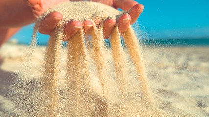 CLOSE UP: Unrecognizable female tourist scatters the sand across the shore.
