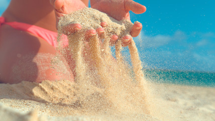 CLOSE UP: Unrecognizable woman in bikini picks up a handful of hot white sand.