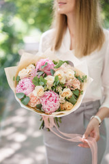 Beautiful summer bouquet. Arrangement with mix flowers. Young girl holding a flower arrangement with peony. The concept of a flower shop. Content for the catalog