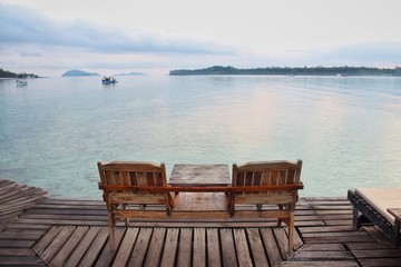 Fototapeta premium Two wooden chair on wooden floor with blue sea background