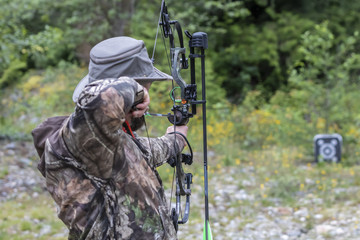 A Man Wearing Camouflage Shooting a Compound Bow 