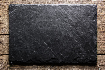 Black slate board on grunge wooden table closeup. Natural texture. Can be used like food background - Powered by Adobe