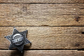 Sheriff star on wooden table closeup. Law concept background