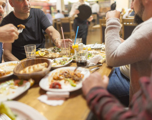 Fototapeta na wymiar Group of Arab people in restaurant enjoying Middle Eastern Iftar food. Selective focus