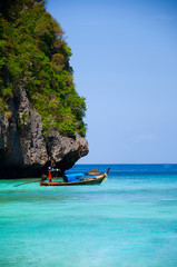 Cliff of Phi Phi island and wooden long tail boat in turquoise Andaman sea Krabi -  Phuket, Thailand