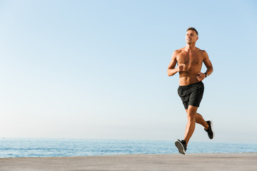 Obraz na płótnie Canvas Happy shirtless sportsman running