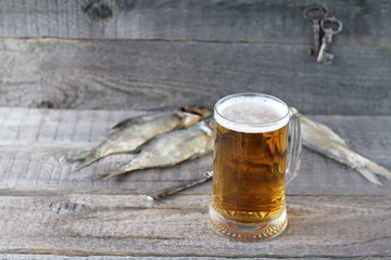 A mug of  light beer and dry fish on a wooden background.