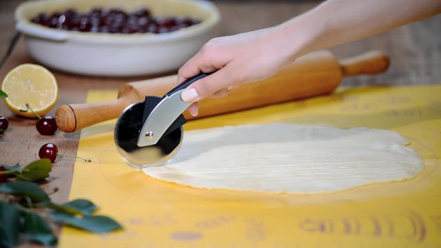Making a cherry pie. Cut short dough into strips.