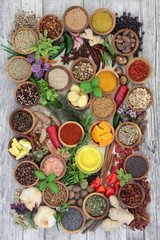 Culinary fresh  and dried herbs and spices for food seasoning with olive oil in bowls and loose forming a colourful rustic abstract background. Top view.