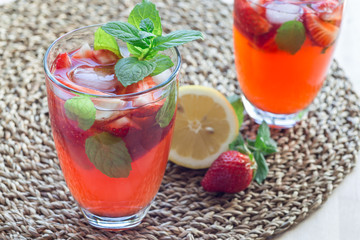 Homemade iced tea with strawberries and mint on wooden table, horizontal