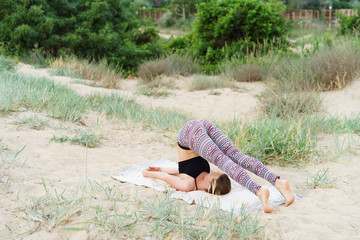 Girl does inverted yoga asanas in the outdoor, the plow pose