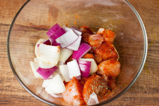 Preparation of chicken skewers with vegetables. Chopped chicken meat lying in bowl with onion, pepper, marinade