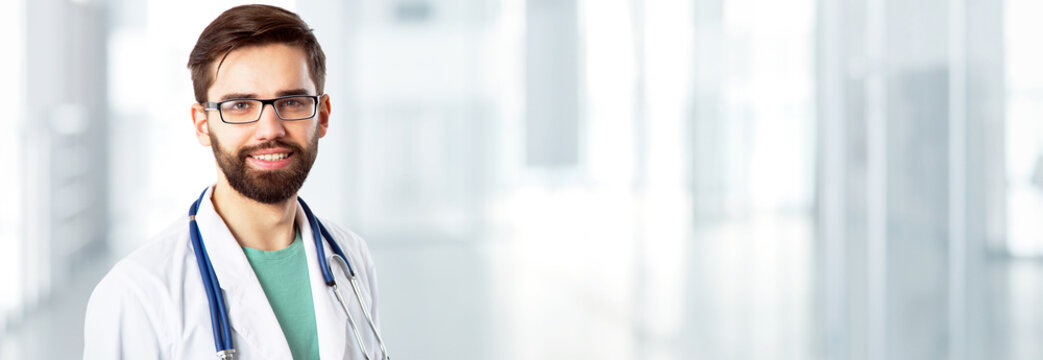 Young handsome doctor on modern clinic background.