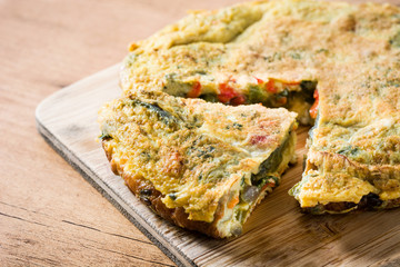 Frittata made of eggs and vegetables on wooden table.