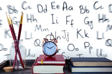 Books with alarm clock with books and paintbrushes on wooden - Powered by Adobe