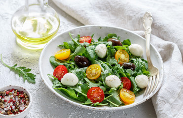 Fresh summer salad with arugula, yellow and red cherry tomatoes, Kalamata olives and mozzarella