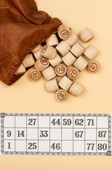 Wooden lotto barrels with brown bag and game card on beige background