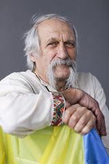 close up studio portrait of old man in the ethnic national costume with ukrainian flag