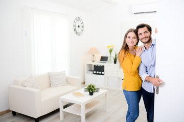 Fototapeta na wymiar cheerful young couple man and woman welcome friends at open front door new student home apartment