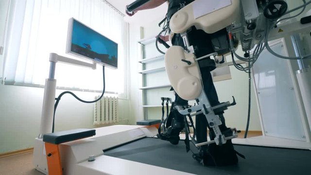 Modern medical recovery device. Disabled man is training to walk with the help of a simulation system