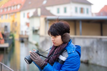 portrait of Asian man Tourist travelling with digital camera in a ribeauville town, colmar, france - one of the oldest medieval town in Alsace.
