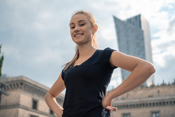 Young blonde woman silhouette in a black tshirt with cityscape in the background
