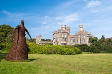 Wicker woman statue and castle in Stornoway, United Kingdom. Willow sculpture on green grounds of Lews Castle estate. Architecture and design. Landmark and attraction. Summer vacation and wanderlust © be free