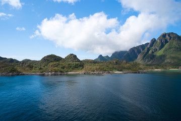 Sea water at mountain coast under cloudy blue sky. Sea on mountain landscape. Beauty of wild nature. Wanderlust and vacation. Water is the driver of nature