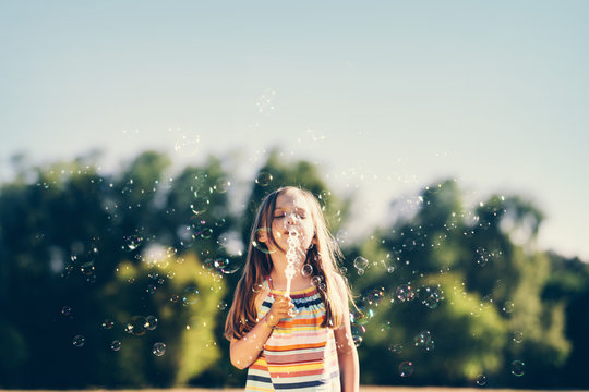 Little girl blowing soap bubbles in the park.