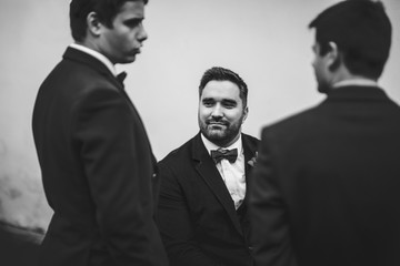 Look from behind groomsmen at a groom on the wheelchair