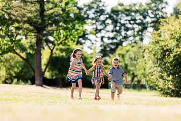 Three happy kids holding hands and running