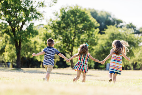 Three little children running on a green field