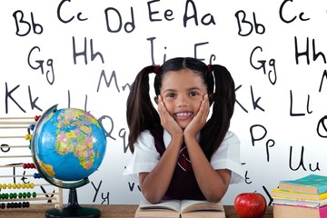 Fototapeta premium Composite image of schoolgirl leaning by globe and books