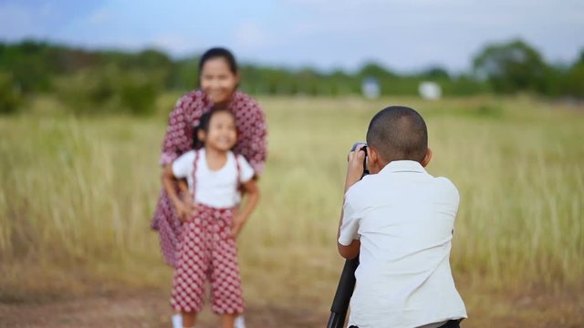 Slow motion Asian family, the boy is taking photos of mother and sister happy in the pasture.