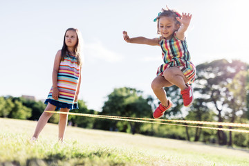 Little girl in a colorful dress jumping through the elastic.