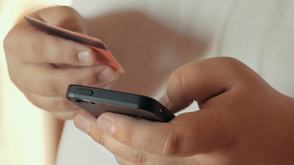 Mobile shopping concept or Online banking. Close up of male hand holding smartphone and credit card in another hand