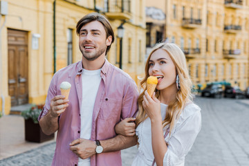 portrait of young couple with ice cream walking on street on summer day