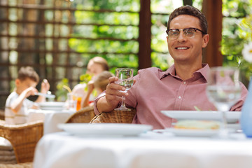 Business dinner. Graceful man wearing glasses having business dinner on summer terrace of the continental restaurant
