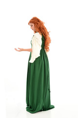 full length portrait of red haired girl wearing long green medieval gown. standing pose, isolated on white studio background.