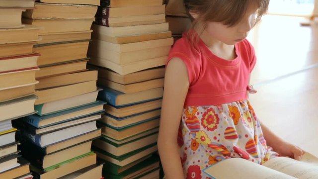 Little girl paging a book sitting on the floor