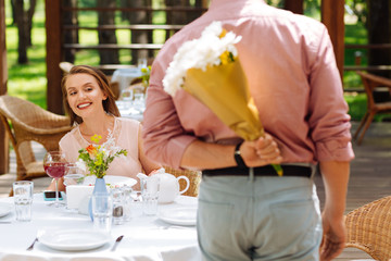Beaming wife. Beaming beautiful wife feeling simply amazing while looking at her handsome husband with flowers
