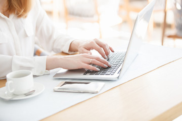 The hands of an unidentified young woman secretary or manager typing text on the laptop keyboard on...