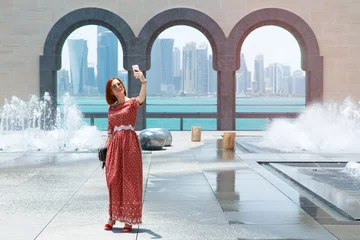 Fotobehang Girl opposite the skyscrapers and the sea in Doha. © Poter_N