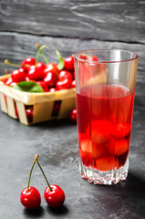 juice or compote with cherries. fresh ripe red cherry in a basket on a gray concrete background, summer berry, summer drink