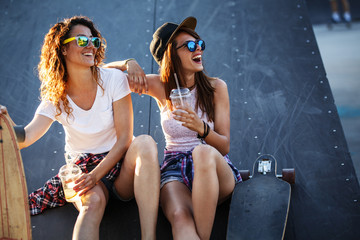 Two female friends hangout at the skate park.Laughing and fun.